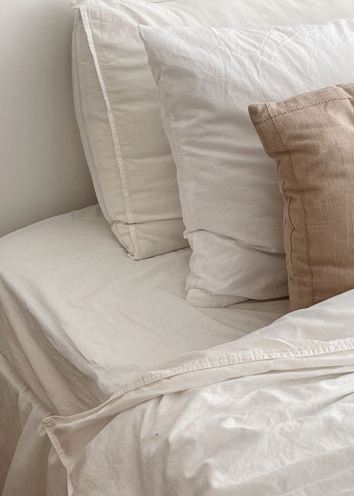 Serene bedroom setting featuring soft, white bedding and neutral pillows for a cozy feel.