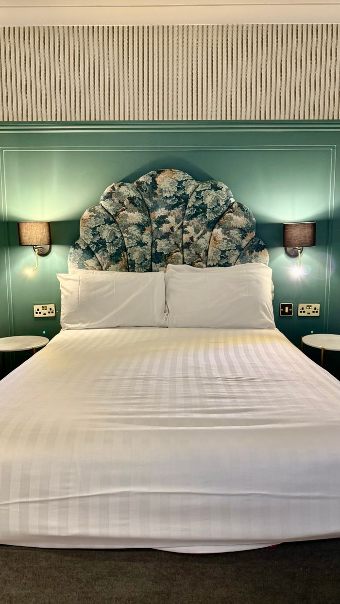 Elegant hotel room interior showcasing a floral headboard and cozy lighting.
