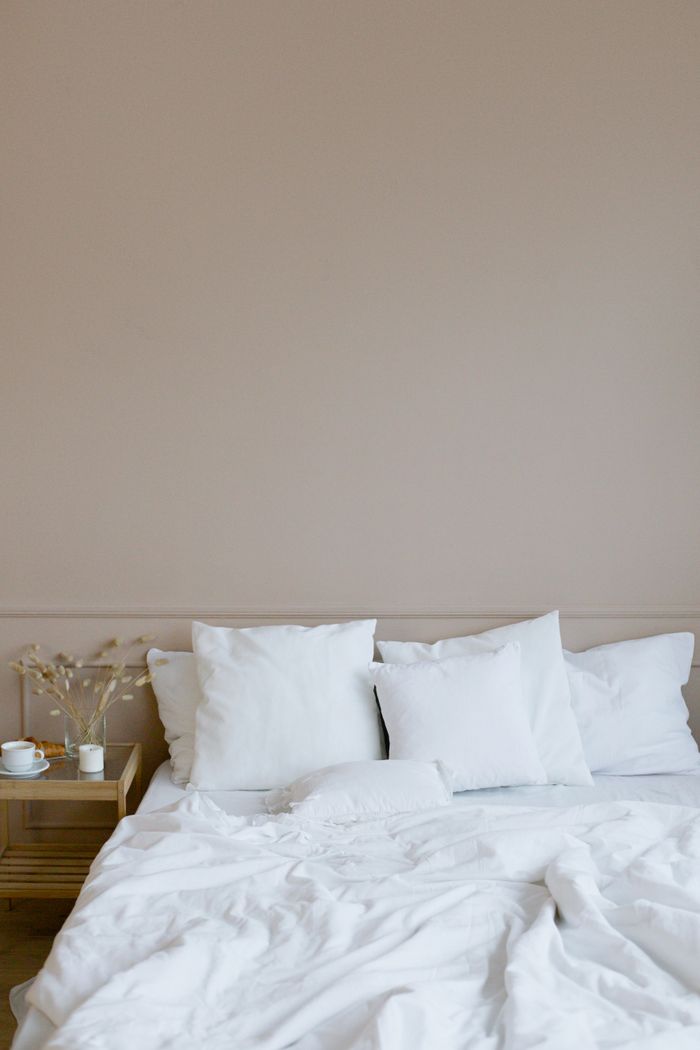 Elegant minimalist bedroom showcasing a neatly arranged white bed with pillows and a side table.